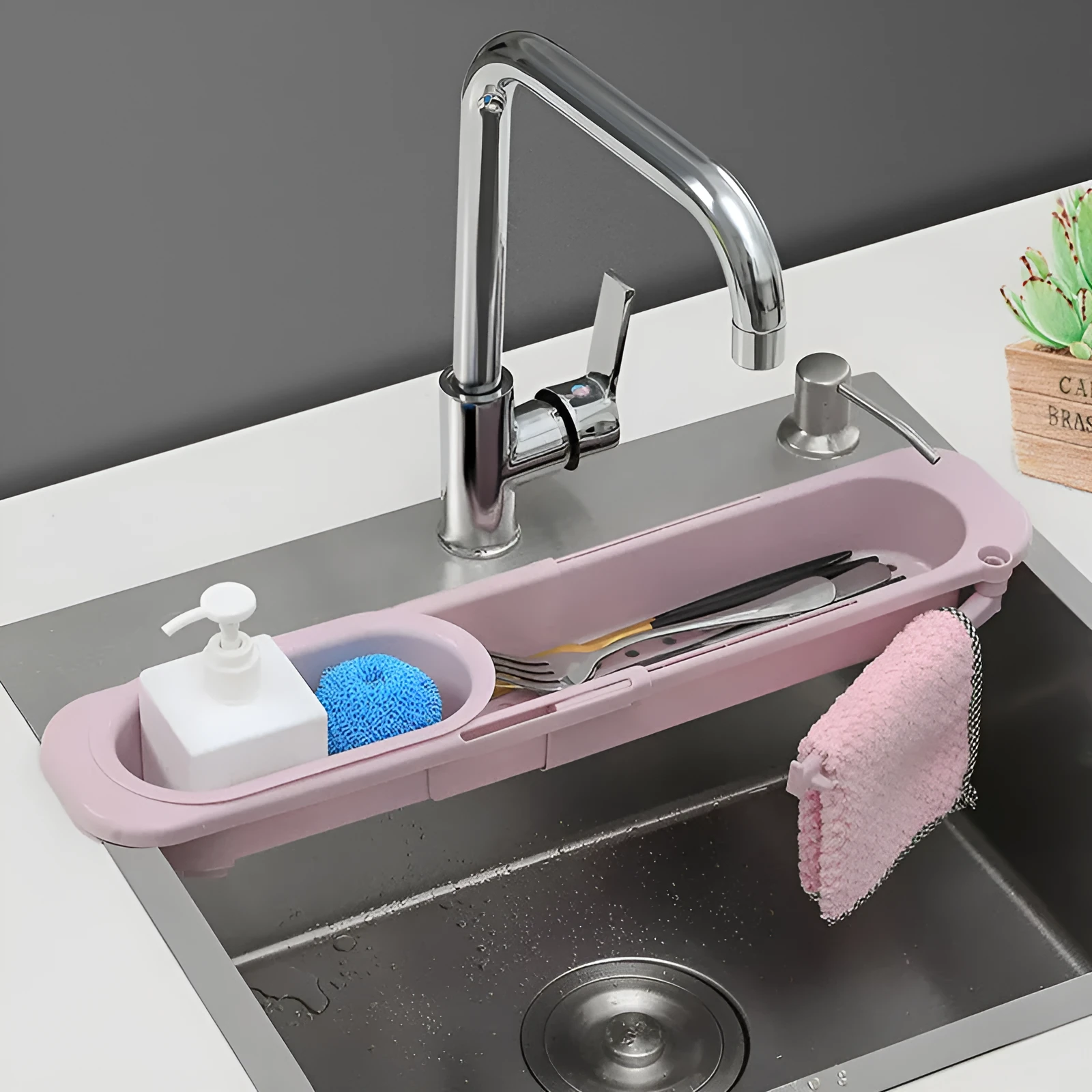 Blue grey telescopic sink rack holding a sponge and soap bar next to a kitchen tap