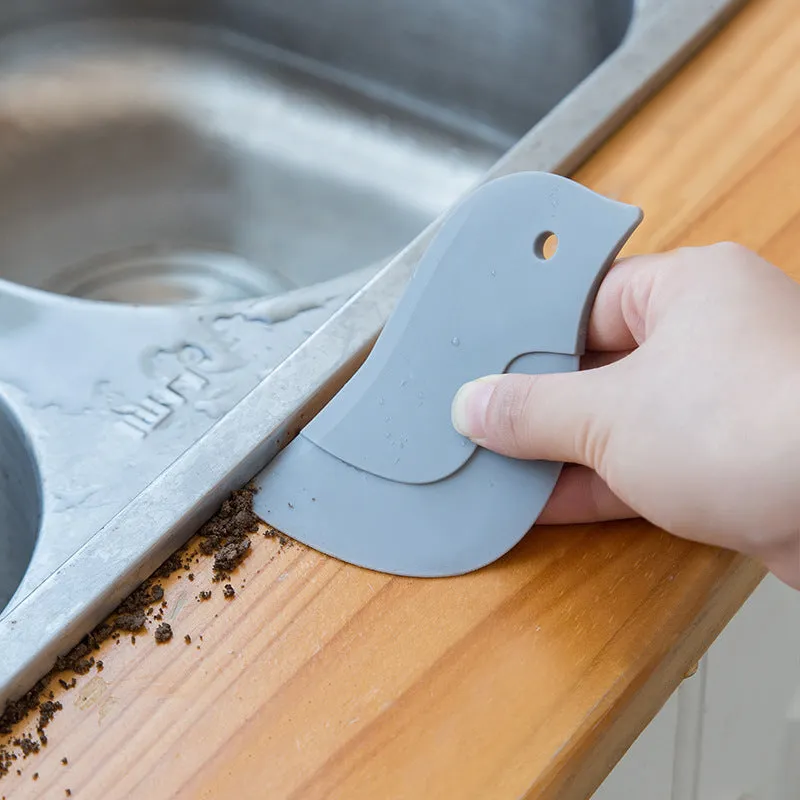 Green penguin-shaped kitchen scraper with soft blade, 11cm by 7cm, for cleaning plates and pots