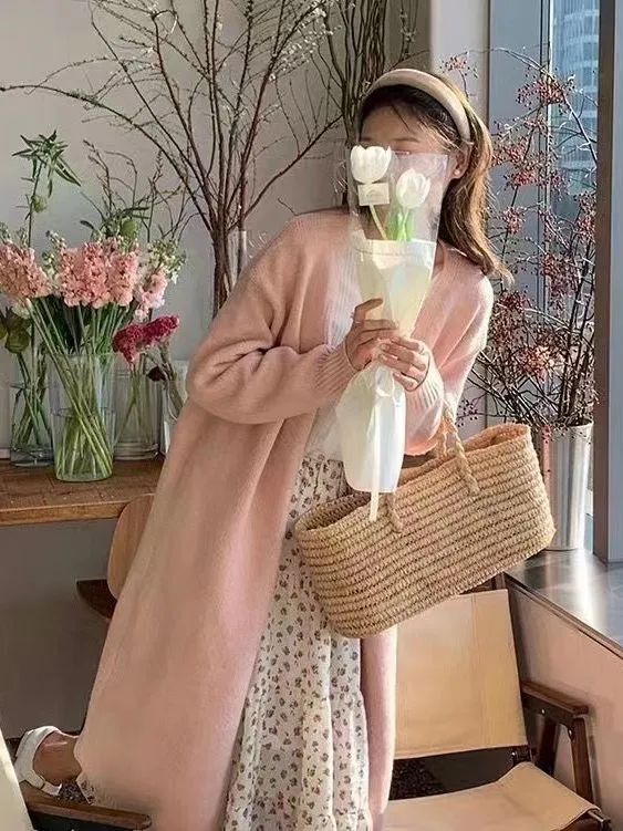 A woman's loose-fit knitted cardigan in a khaki colour with a V-neck and long sleeves, laid flat.