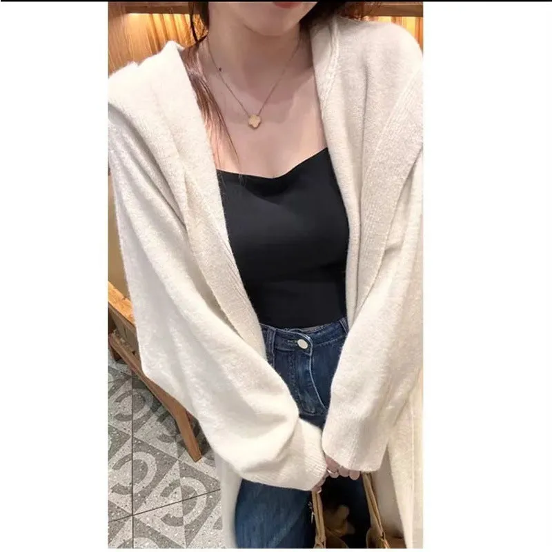 A woman wearing a long, loose, beige hooded knitted cardigan in a Korean casual style.
