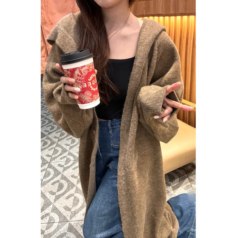 A woman wearing a long, loose, beige hooded knitted cardigan in a Korean casual style.