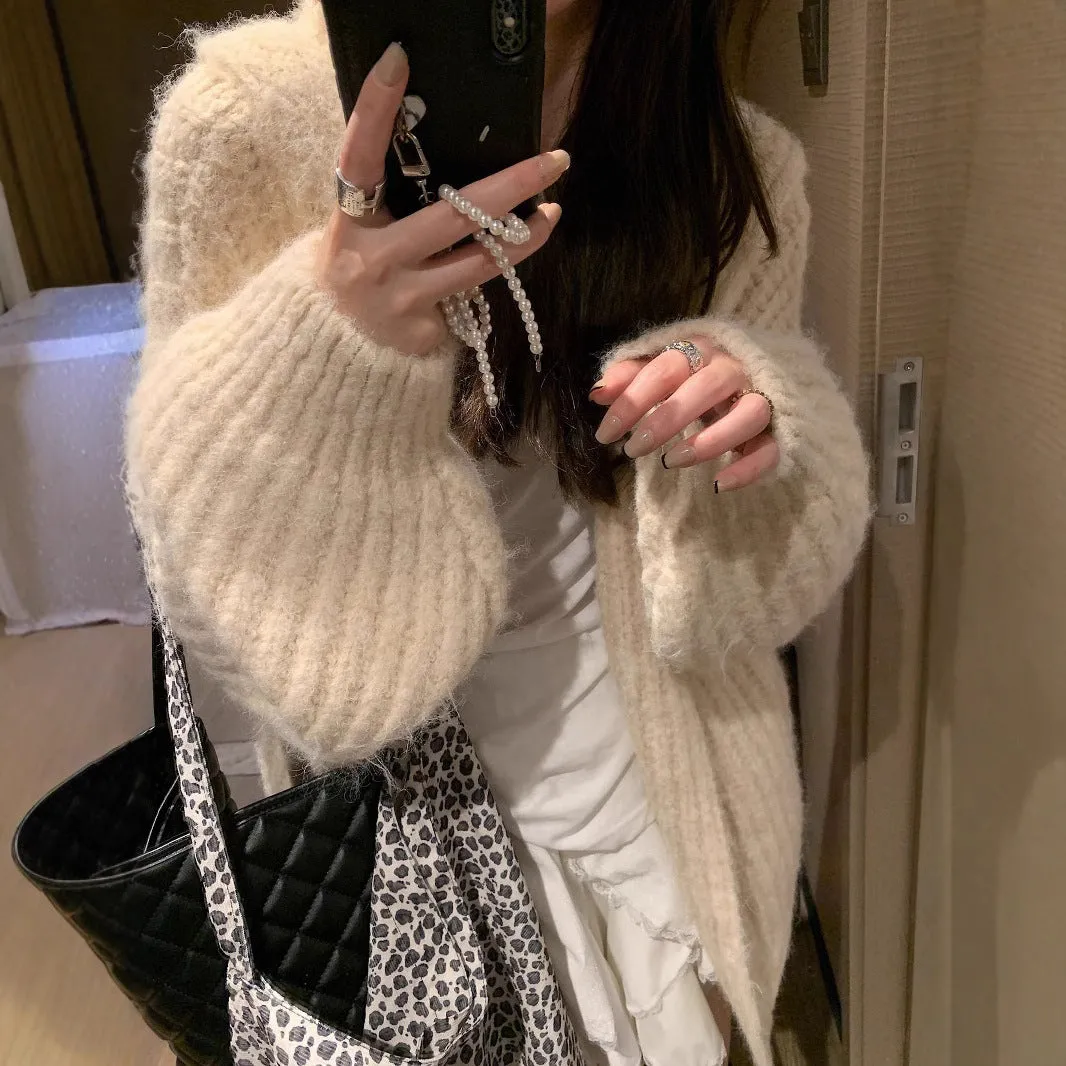 A woman wearing a thick, loose-fit, dark grey hooded sweater cardigan with a retro design.