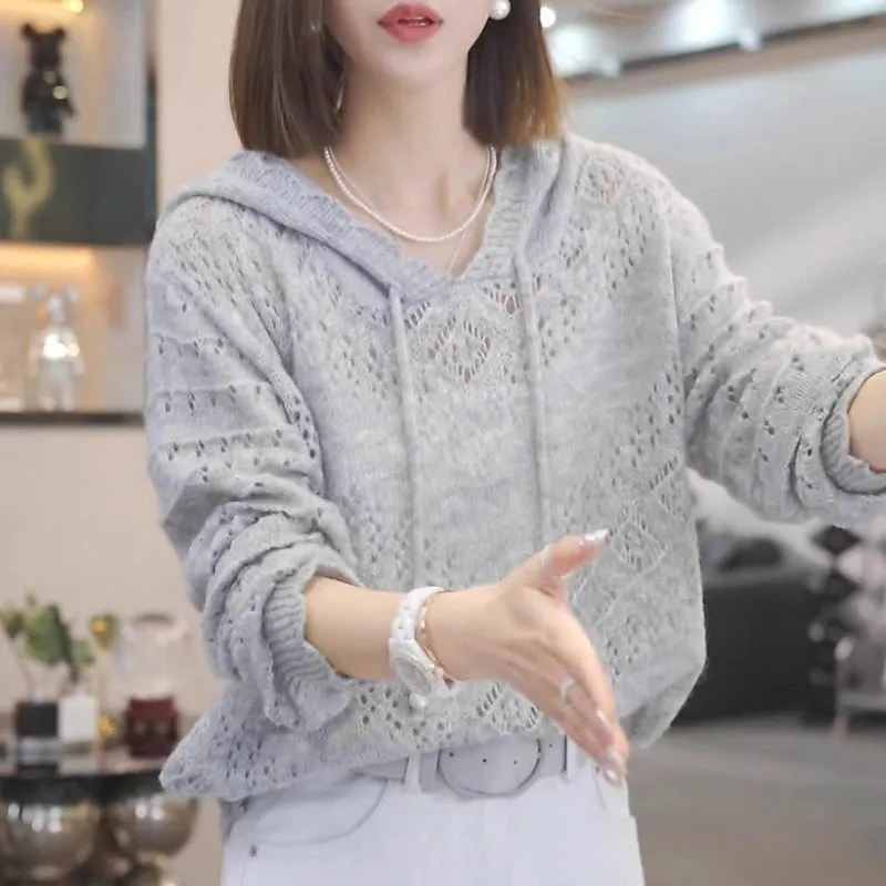 Women's blue crochet hollow knit hooded longsuit undershirt with long sleeves on a hanger.