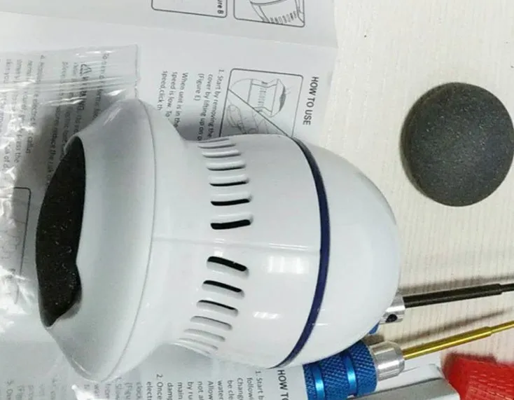 Beige and white electric foot file grinder with USB cable and two diamond grinding heads on a plain background