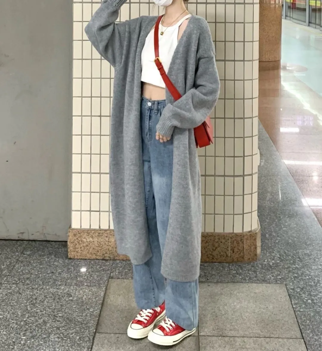 Loose large dark grey knitted cardigan with a 3D pattern, worn open over a top.
