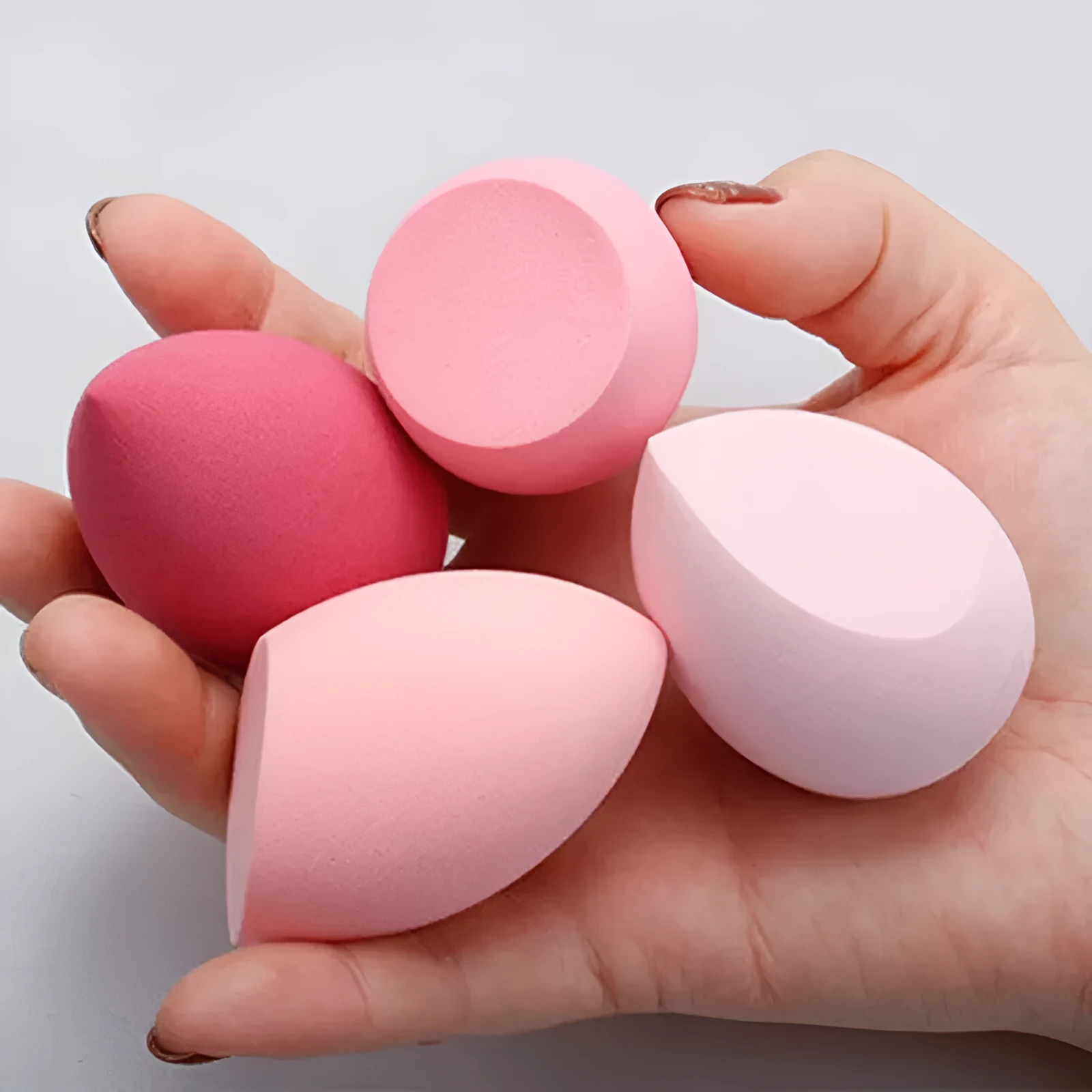 Seven different shaped makeup sponge puffs in various colours including pink, blue and burgundy