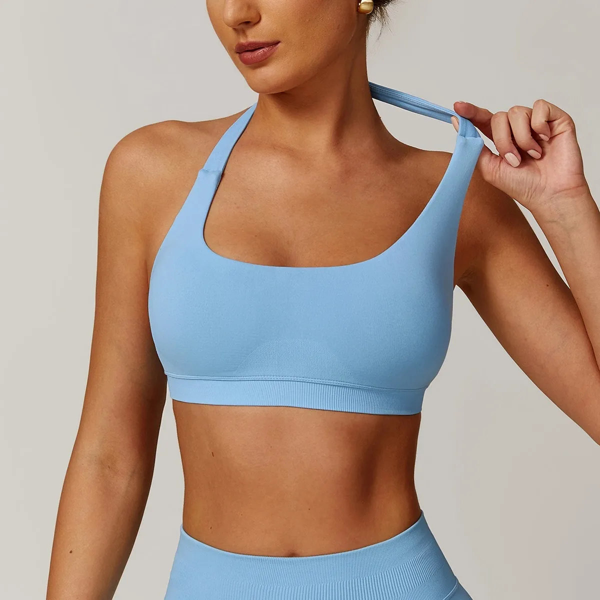 Women's black halter neck sports bra for yoga, shown from the front, with removable pads and a backless design.