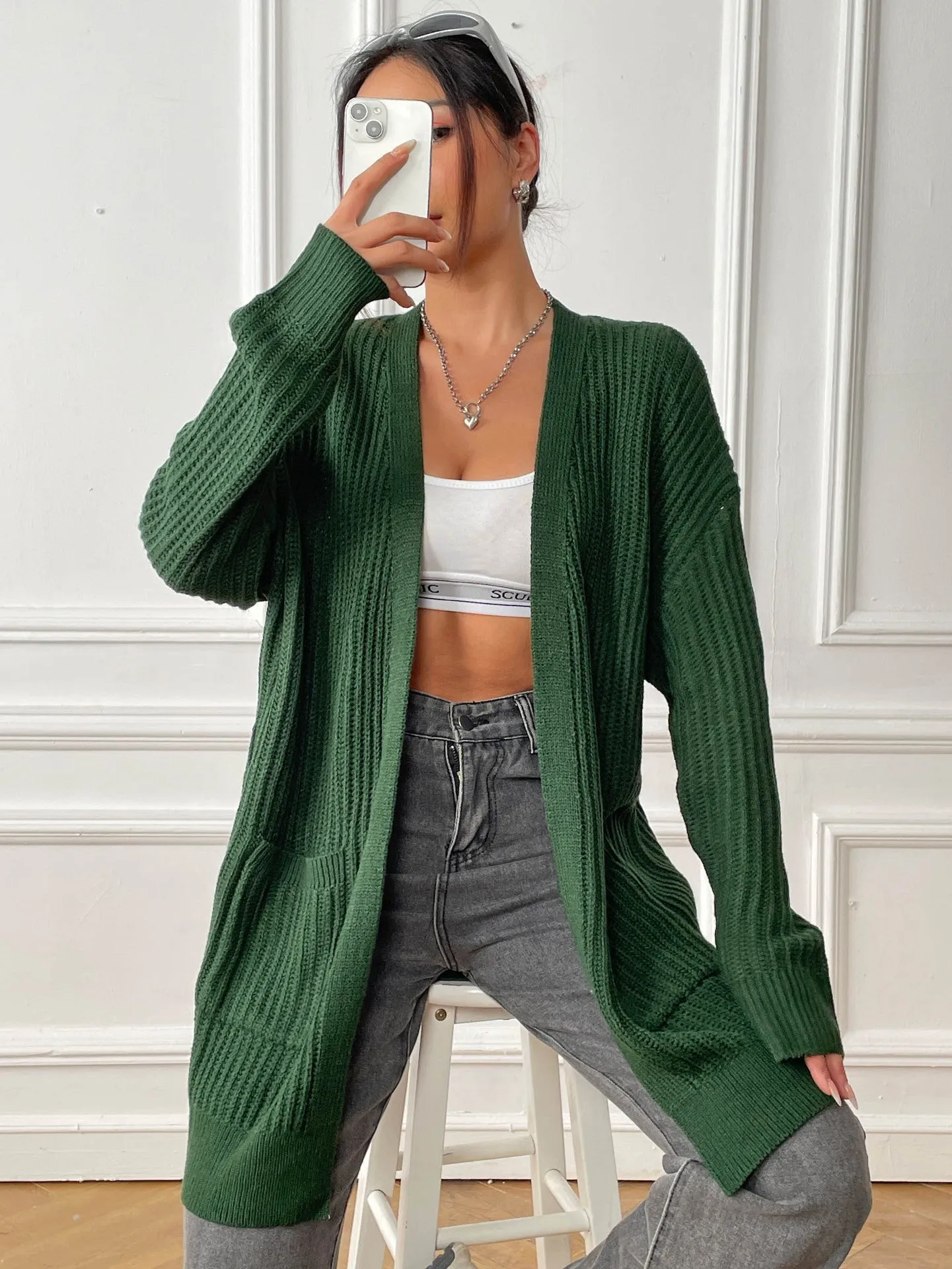 Women's loose fit acrylic cardigan with double pockets in dark green colour showing mid-length design