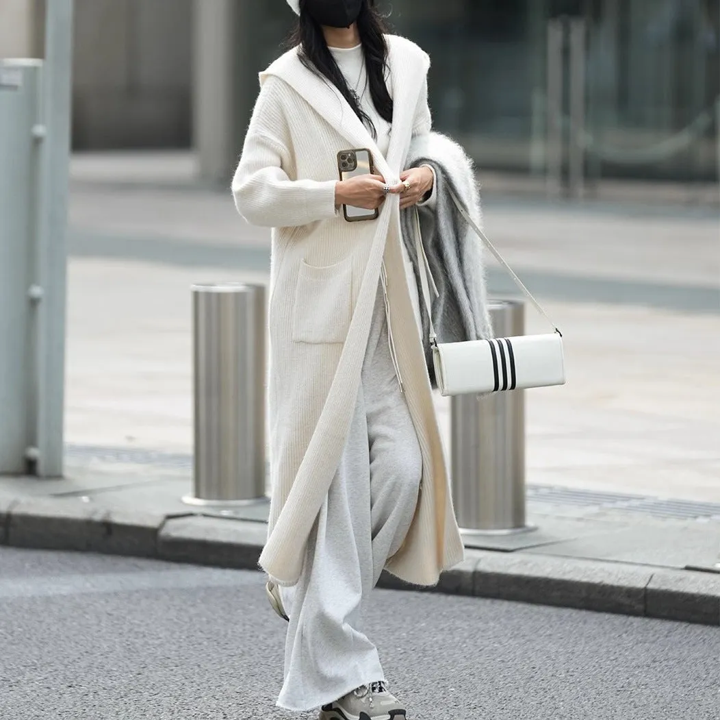 Long grey knitted hooded cardigan trench coat on a hanger, showing loose fit and length.