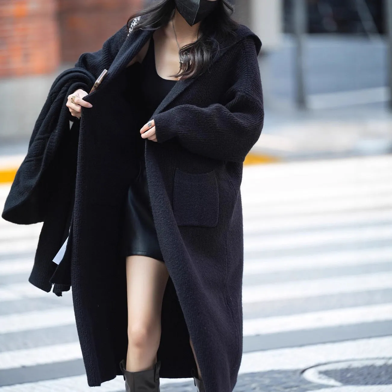 Long grey knitted hooded cardigan trench coat on a hanger, showing loose fit and length.