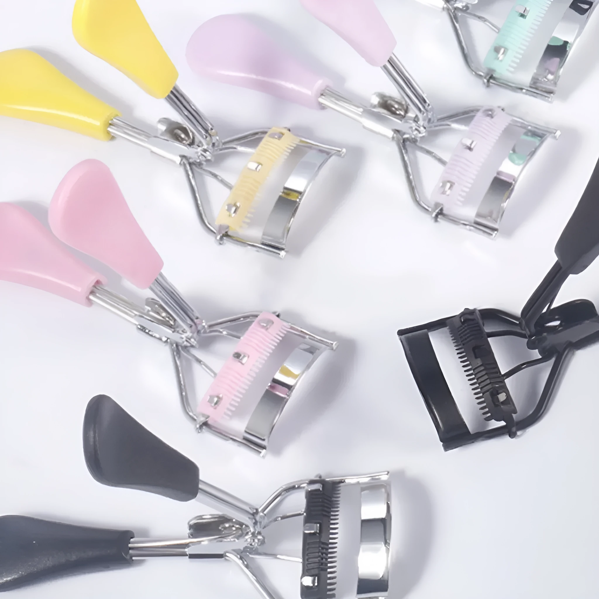 Manual A4 eyelash curler with comb in carbon steel and ABS plastic, shown in a selection of colours.