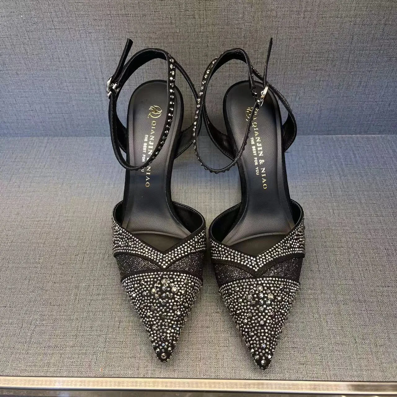 A pair of women's black hollow high heels with a red sole, stiletto heel, and pointed toe.