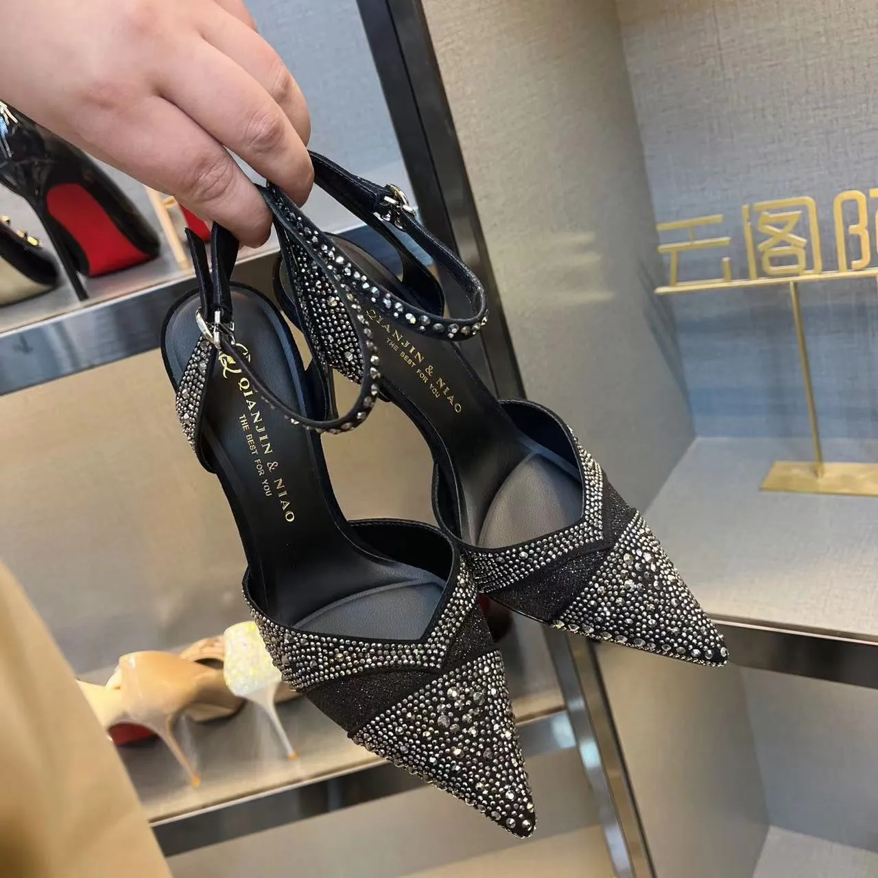 A pair of women's black hollow high heels with a red sole, stiletto heel, and pointed toe.