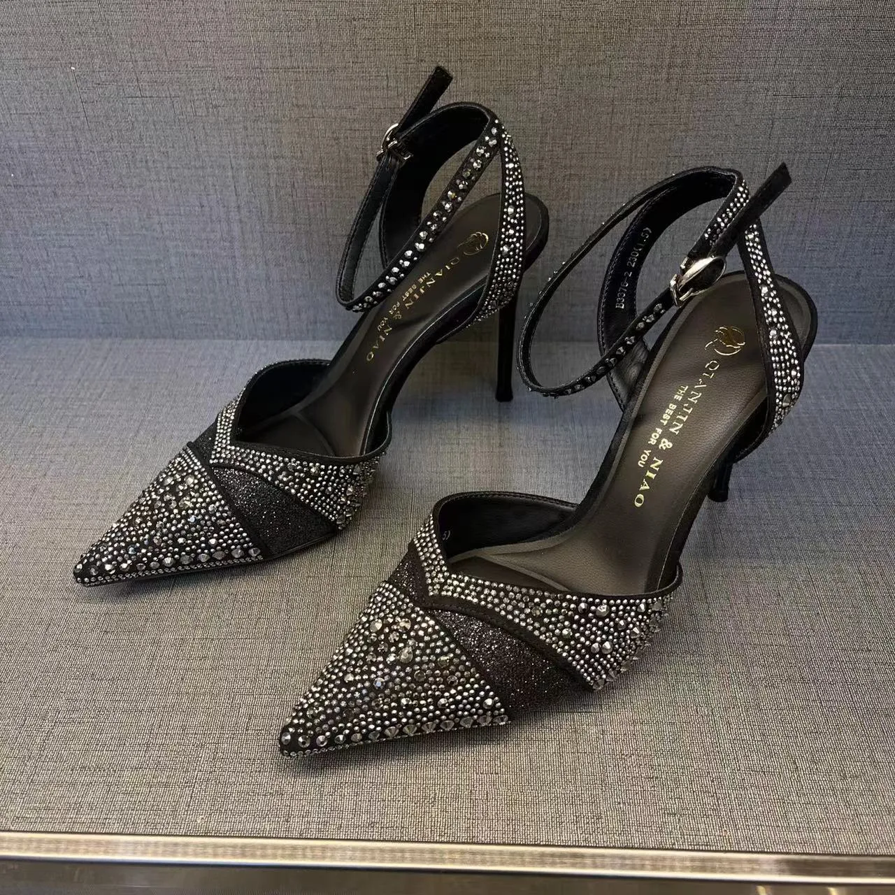 A pair of women's black hollow high heels with a red sole, stiletto heel, and pointed toe.