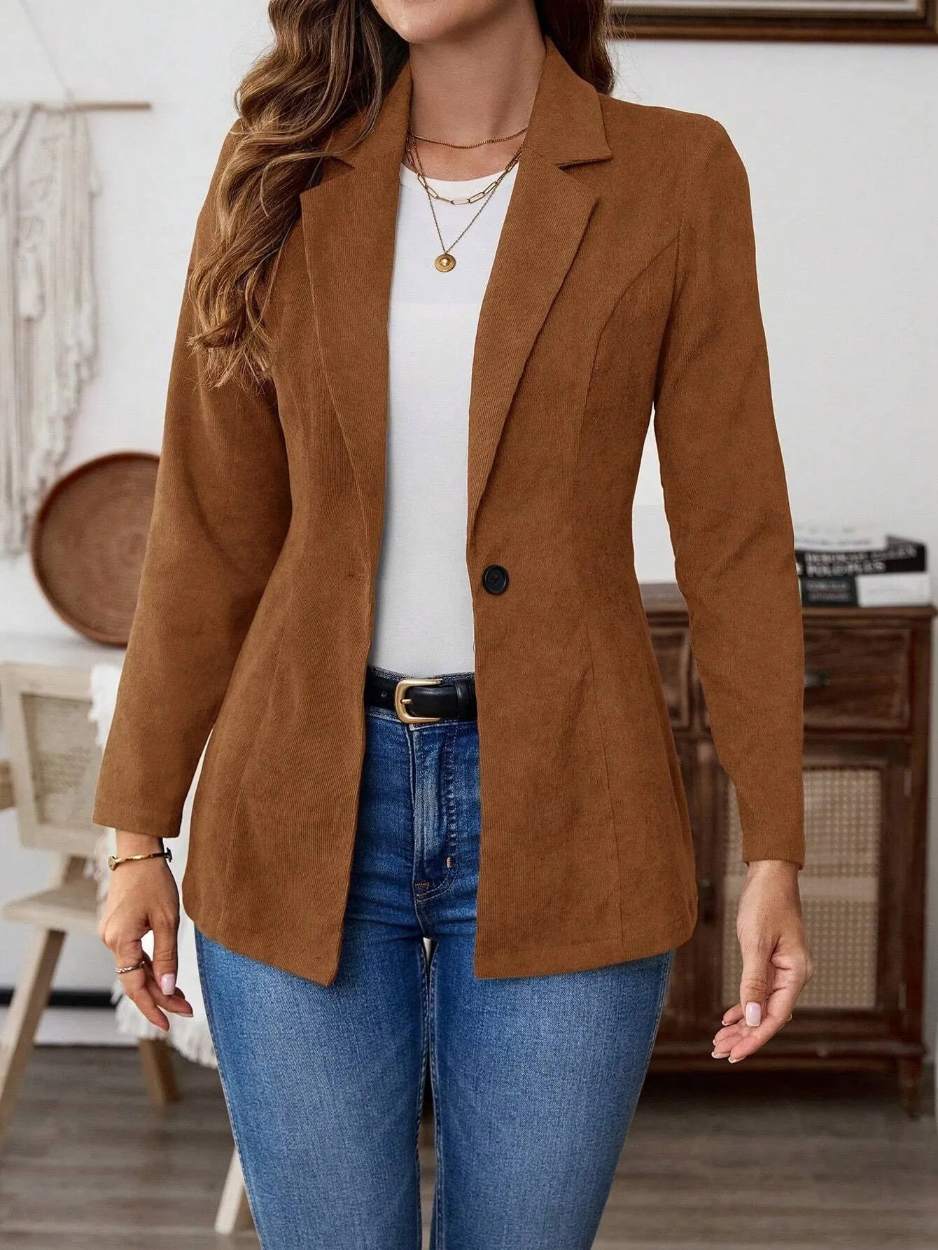 A brown men's single-breasted lapel suit coat with long sleeves on a hanger.