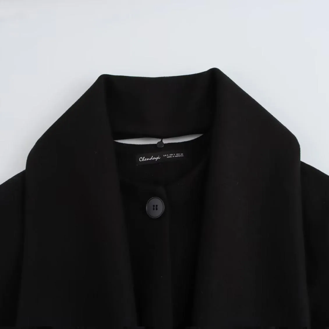 Women's long black coat with artificial fur collar, showing extended length and pocket detail.