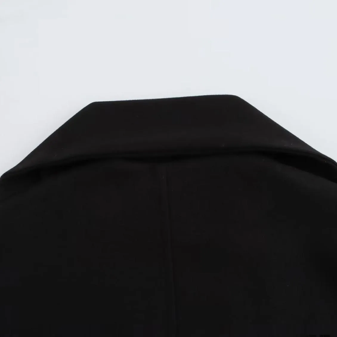 Women's long black coat with artificial fur collar, showing extended length and pocket detail.