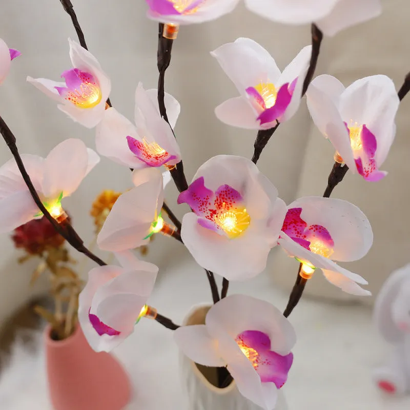 Pink Phalaenopsis-shaped LED decorative light with a bendable 65cm fabric branch on a wooden table.