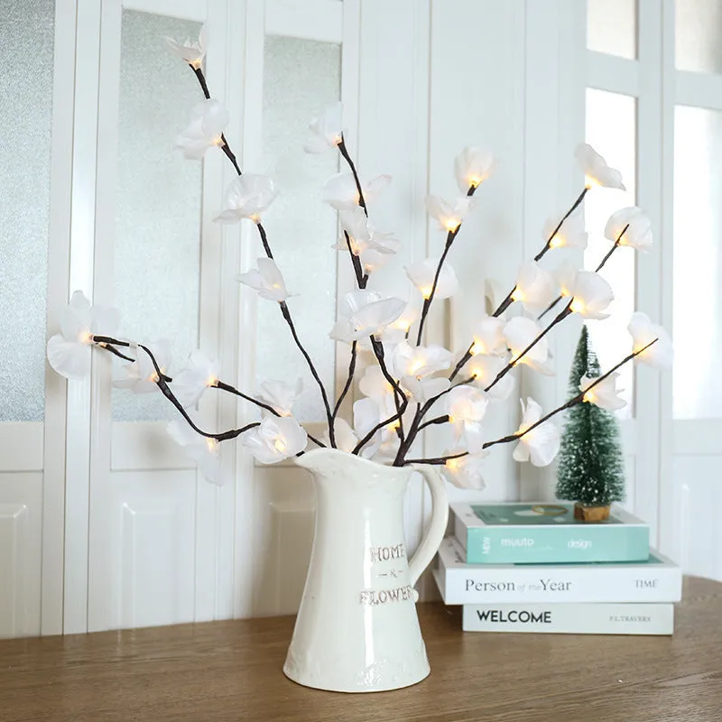 Pink Phalaenopsis-shaped LED decorative light with a bendable 65cm fabric branch on a wooden table.