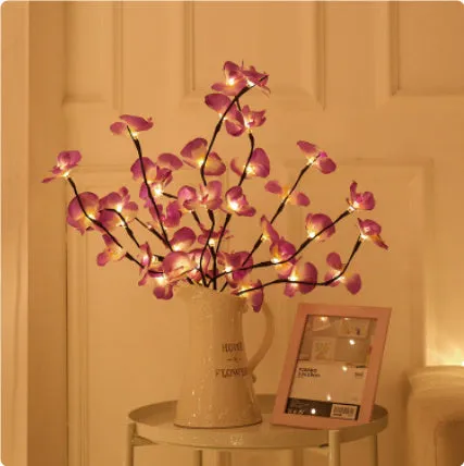 Pink Phalaenopsis-shaped LED decorative light with a bendable 65cm fabric branch on a wooden table.
