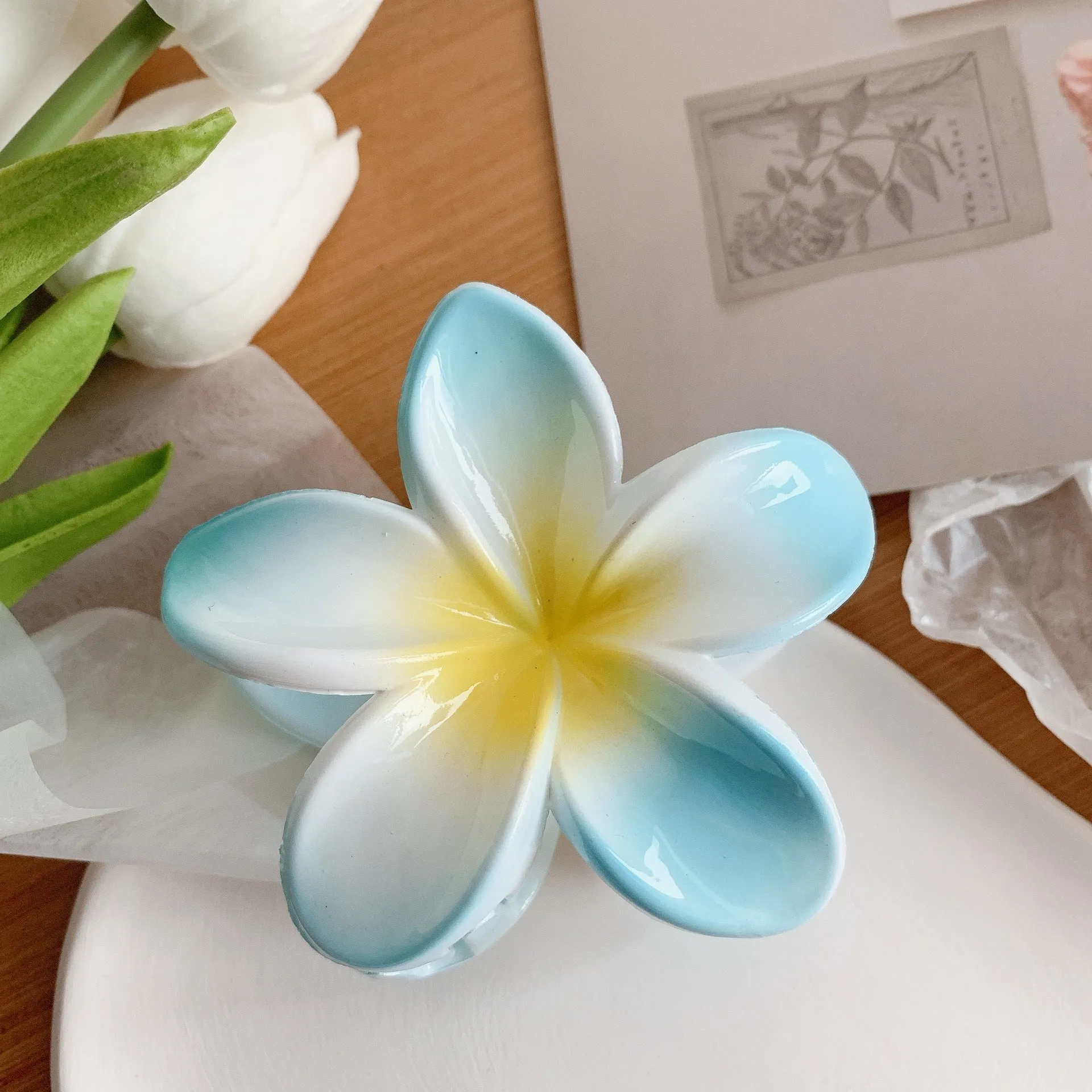 Muweordy plumeria hair claw clip in blue, a decorative flower hair accessory made from plastic and resin.