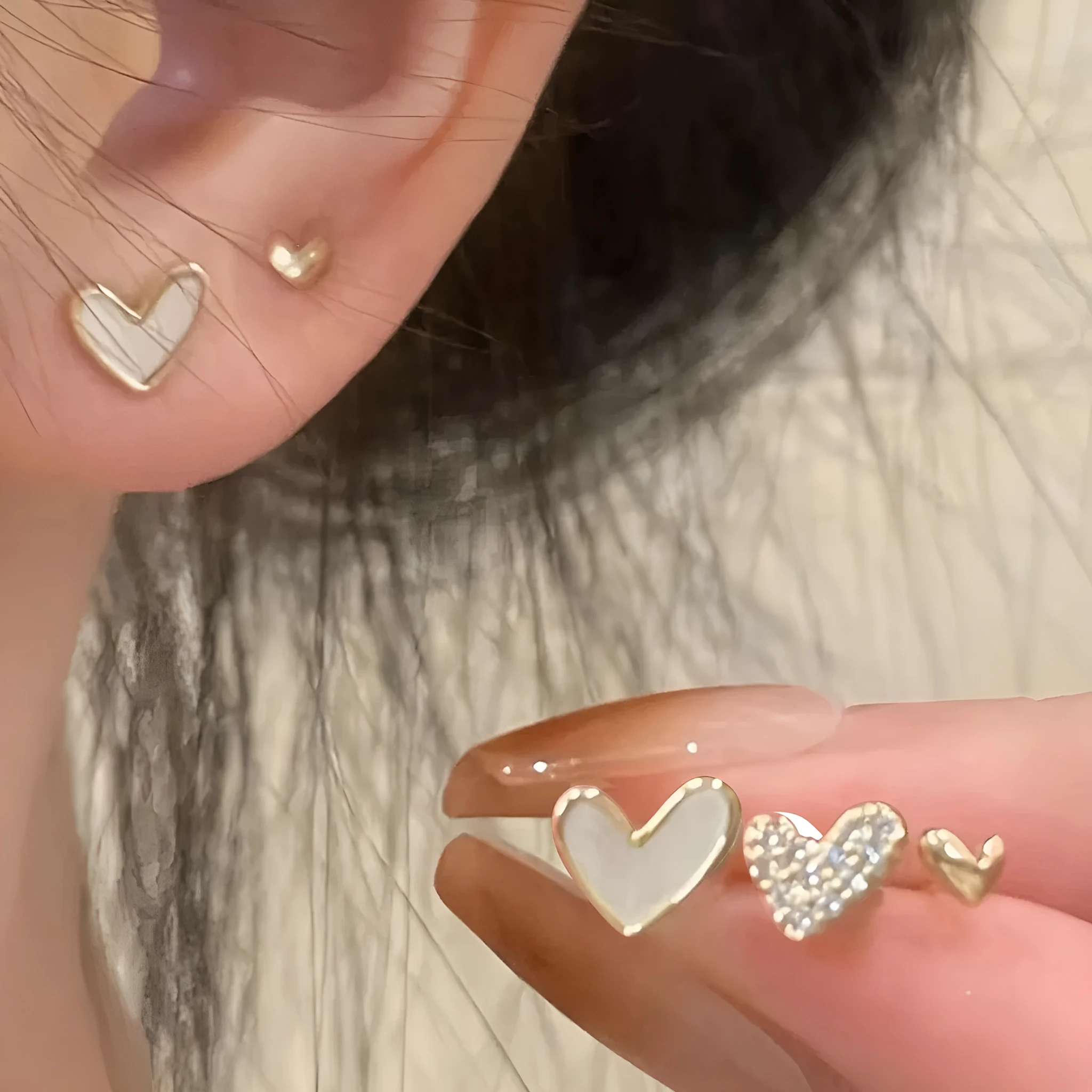 Set of three pairs of women's heart-shaped alloy earrings in gold, black, white, and pink.