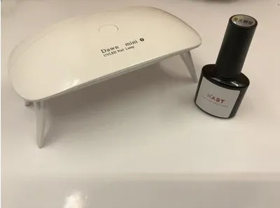 Portable nail dryer in white colour with phototherapy lamp and sealing function on a table