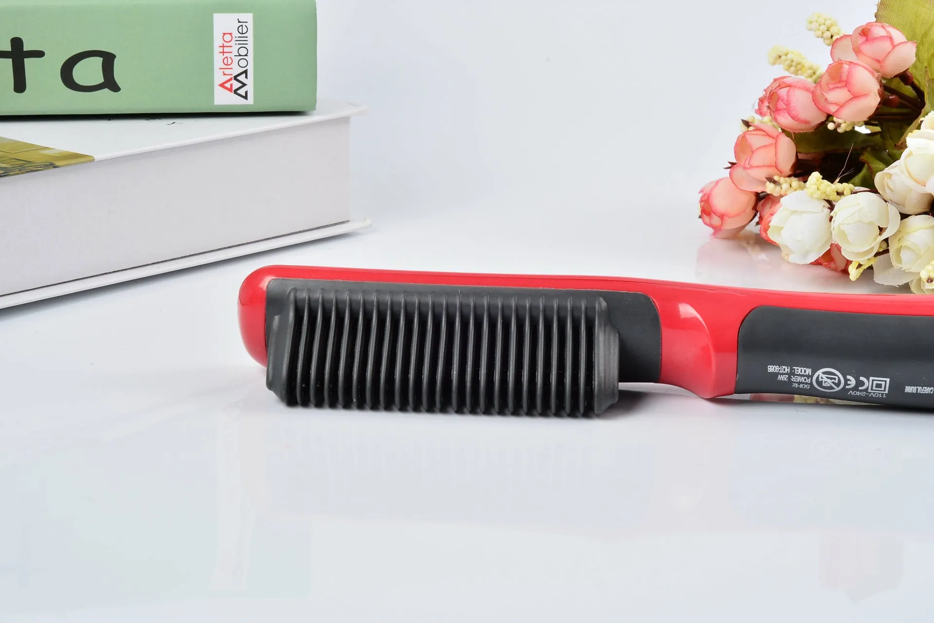 Black and red ceramic hair straightening brush with heated teeth and LED display on white background
