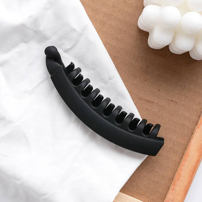 Banana hair clip claw with matte finish in black showing U-shaped design and oversized teeth