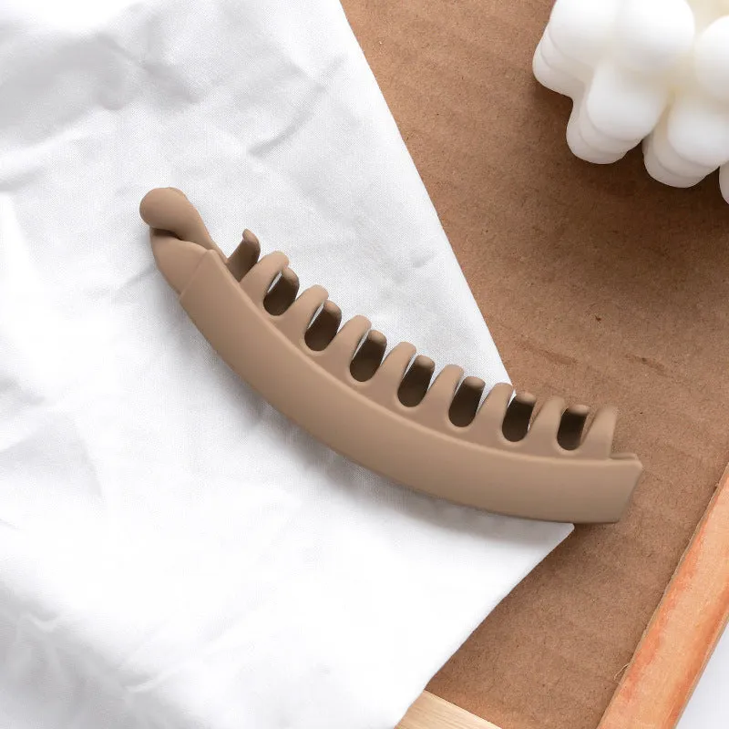 Banana hair clip claw with matte finish in black showing U-shaped design and oversized teeth