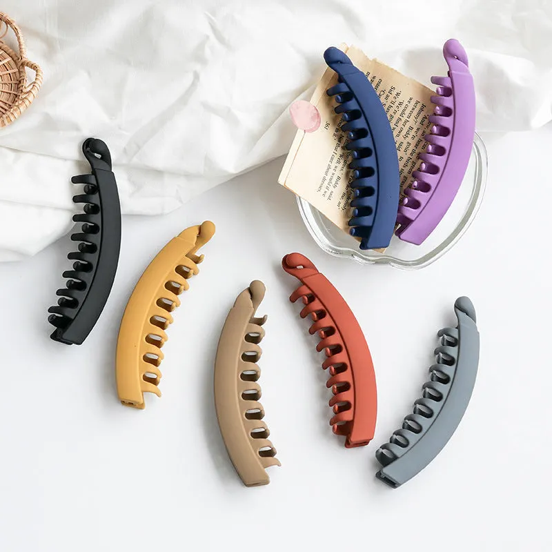 Banana hair clip claw with matte finish in black showing U-shaped design and oversized teeth