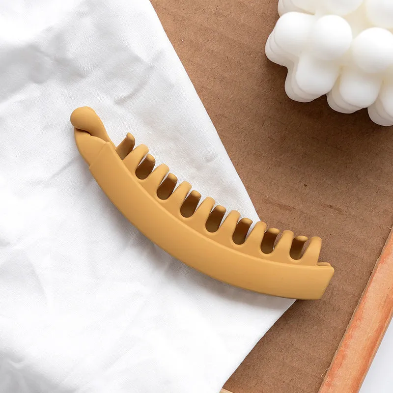 Banana hair clip claw with matte finish in black showing U-shaped design and oversized teeth