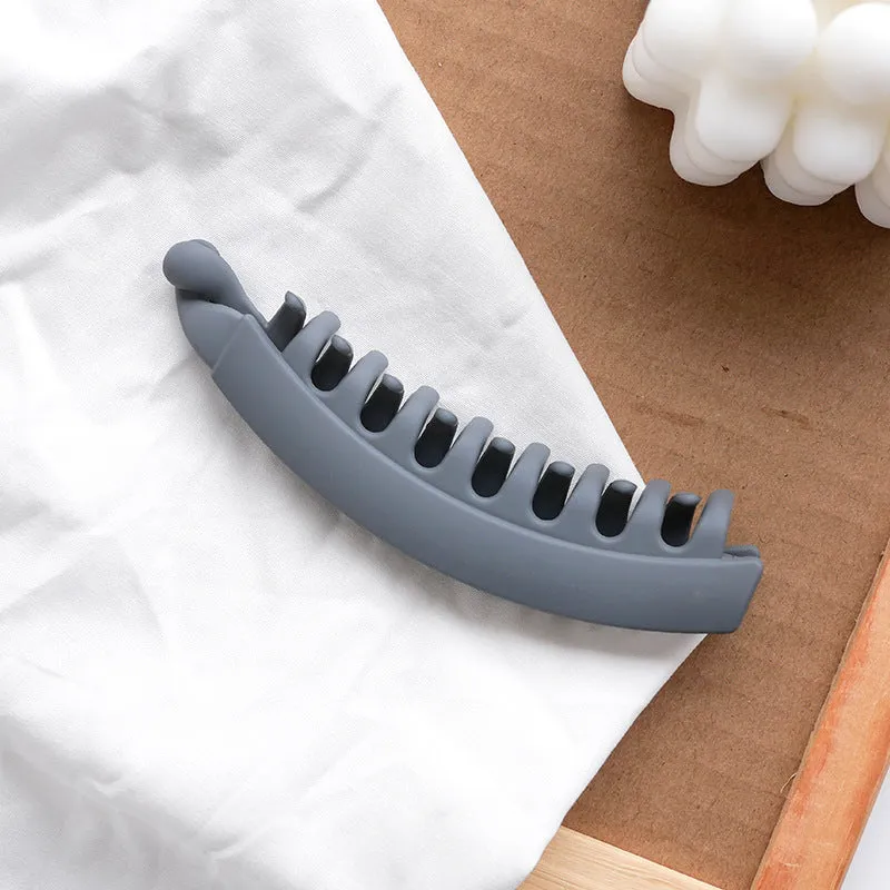 Banana hair clip claw with matte finish in black showing U-shaped design and oversized teeth