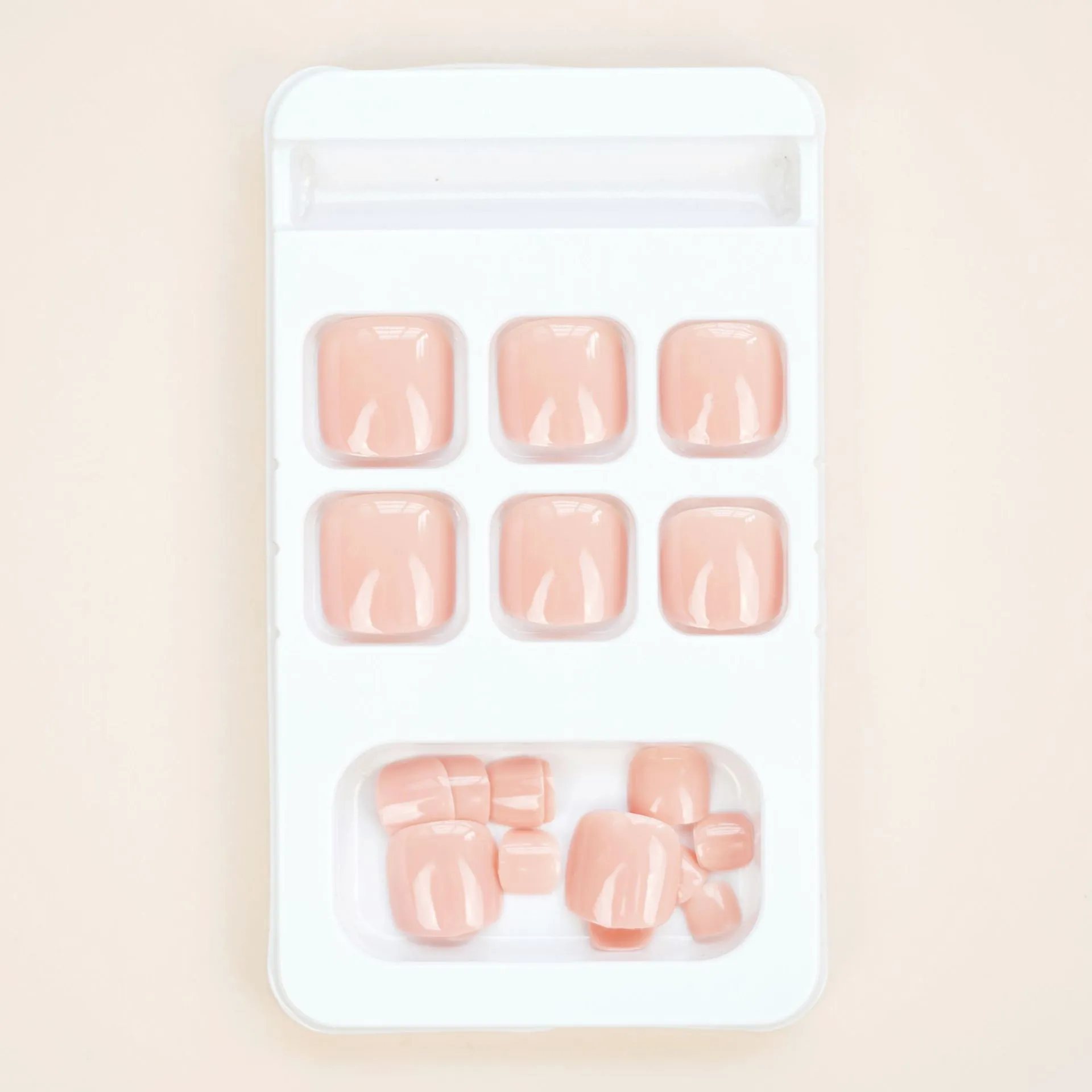 Finished plastic toe nail stickers in J-52 skin colour with glue tube on white background.