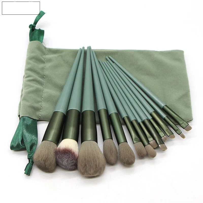 13 green makeup brushes with fibre wool bristles and aluminium tubes arranged on a surface