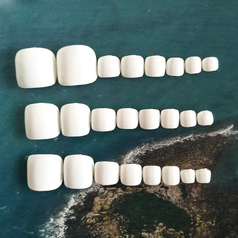 Set of white false nails with a starry sky pattern and glue adhesive for application.