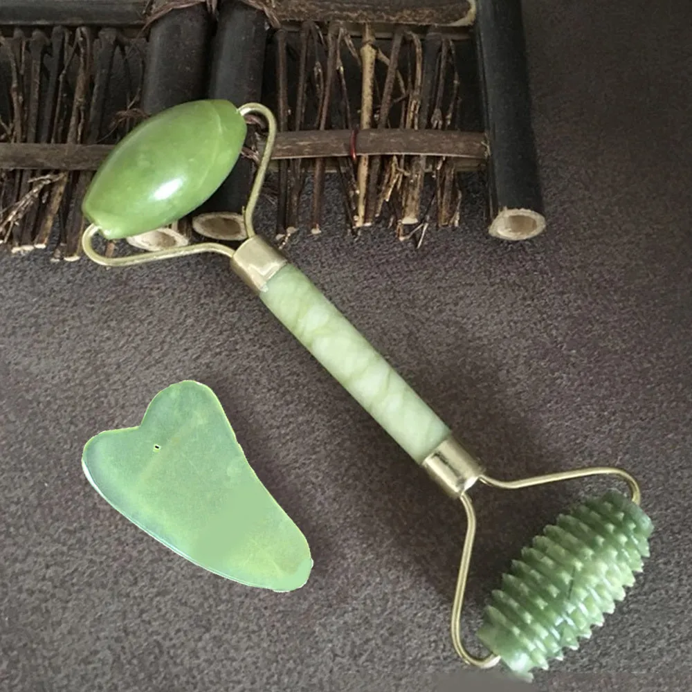 Natural green jade face massager roller and scraper set on a clean surface