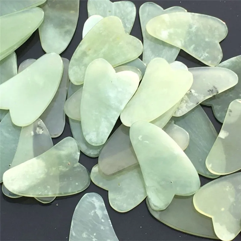 Natural jade gua sha scraper in heart shape on a light surface, 6.3cm x 4.5cm, hand-polished stone
