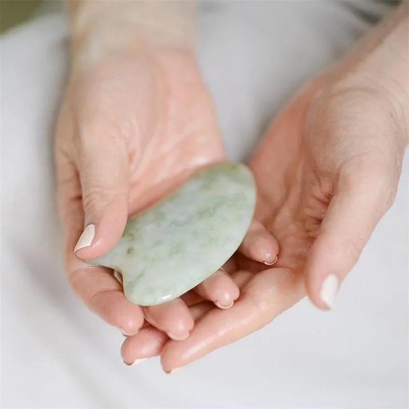Natural jade gua sha scraper in heart shape on a light surface, 6.3cm x 4.5cm, hand-polished stone