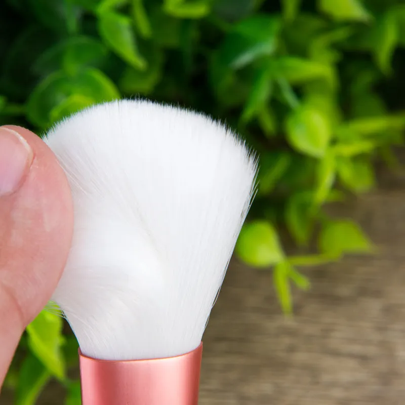12 pink makeup brushes with synthetic hair bristles and plastic handles on a light surface