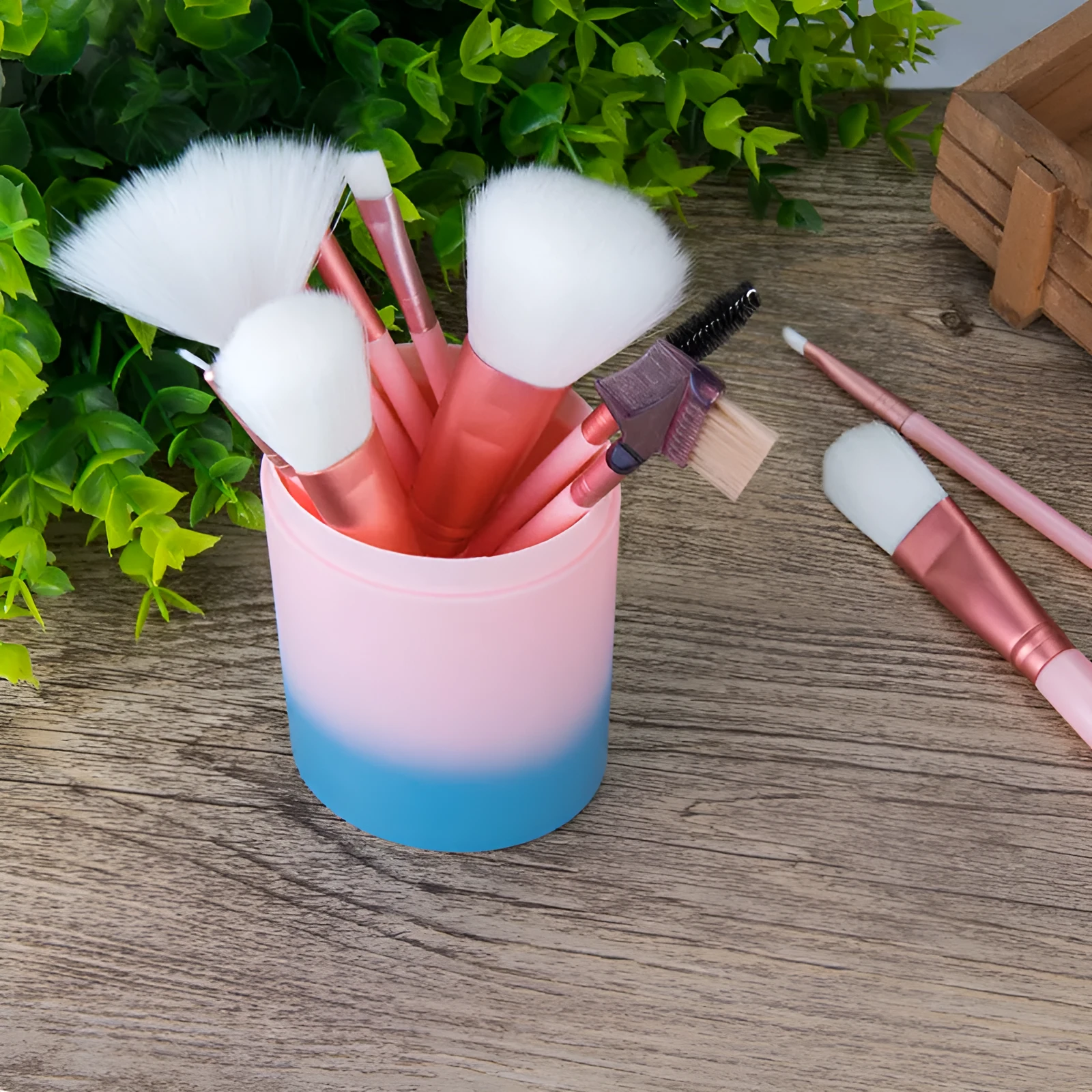 12 pink makeup brushes with synthetic hair bristles and plastic handles on a light surface