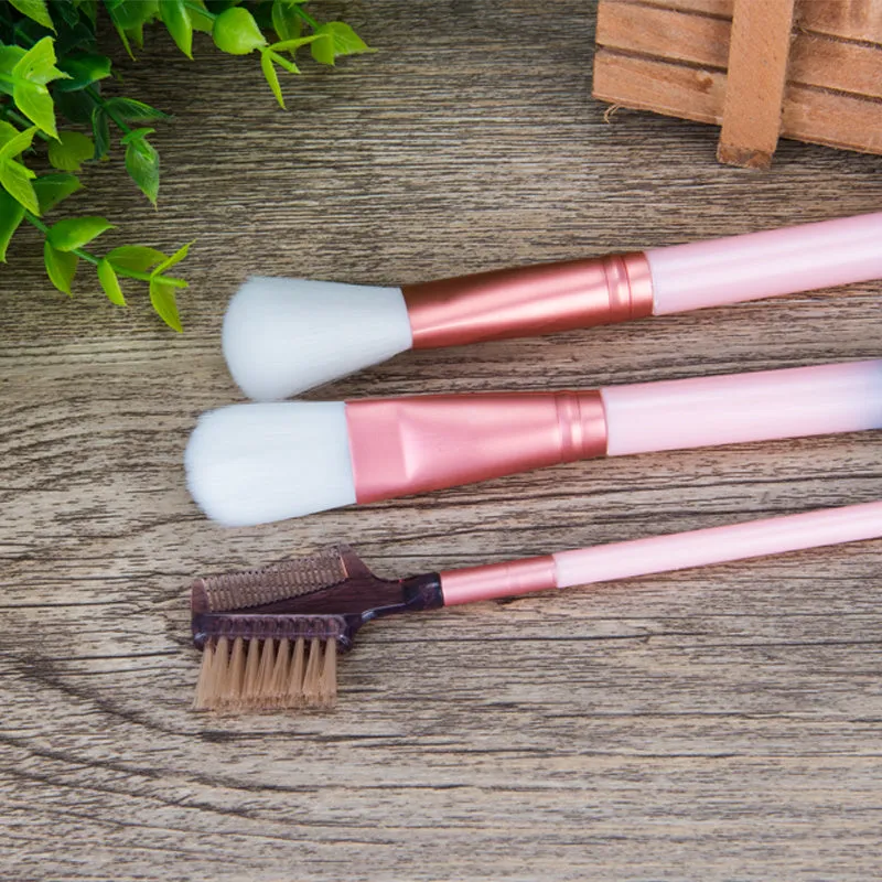 12 pink makeup brushes with synthetic hair bristles and plastic handles on a light surface