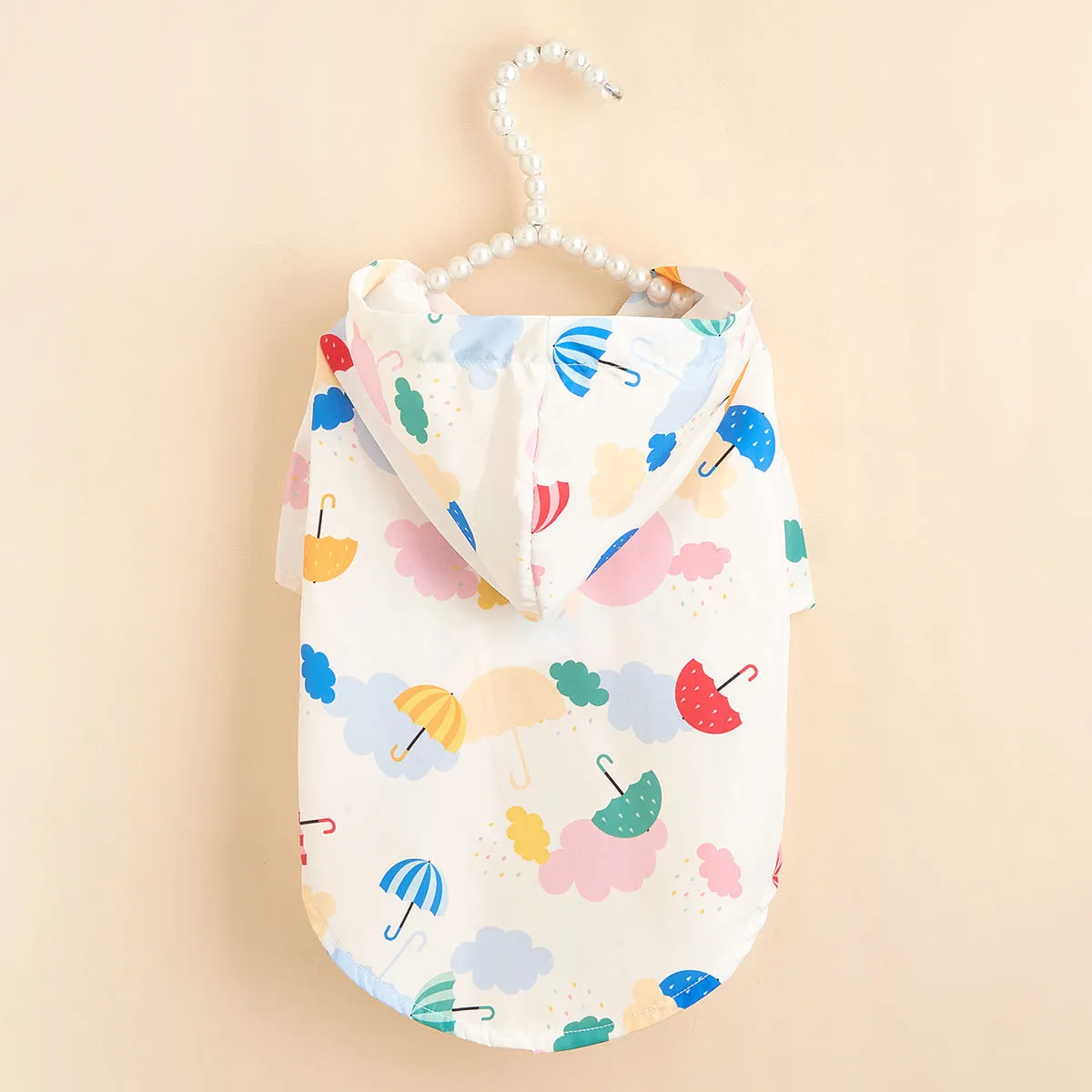 Colourful cartoon umbrella pattern dog raincoat on a model, showing four leg openings and polyester fabric.