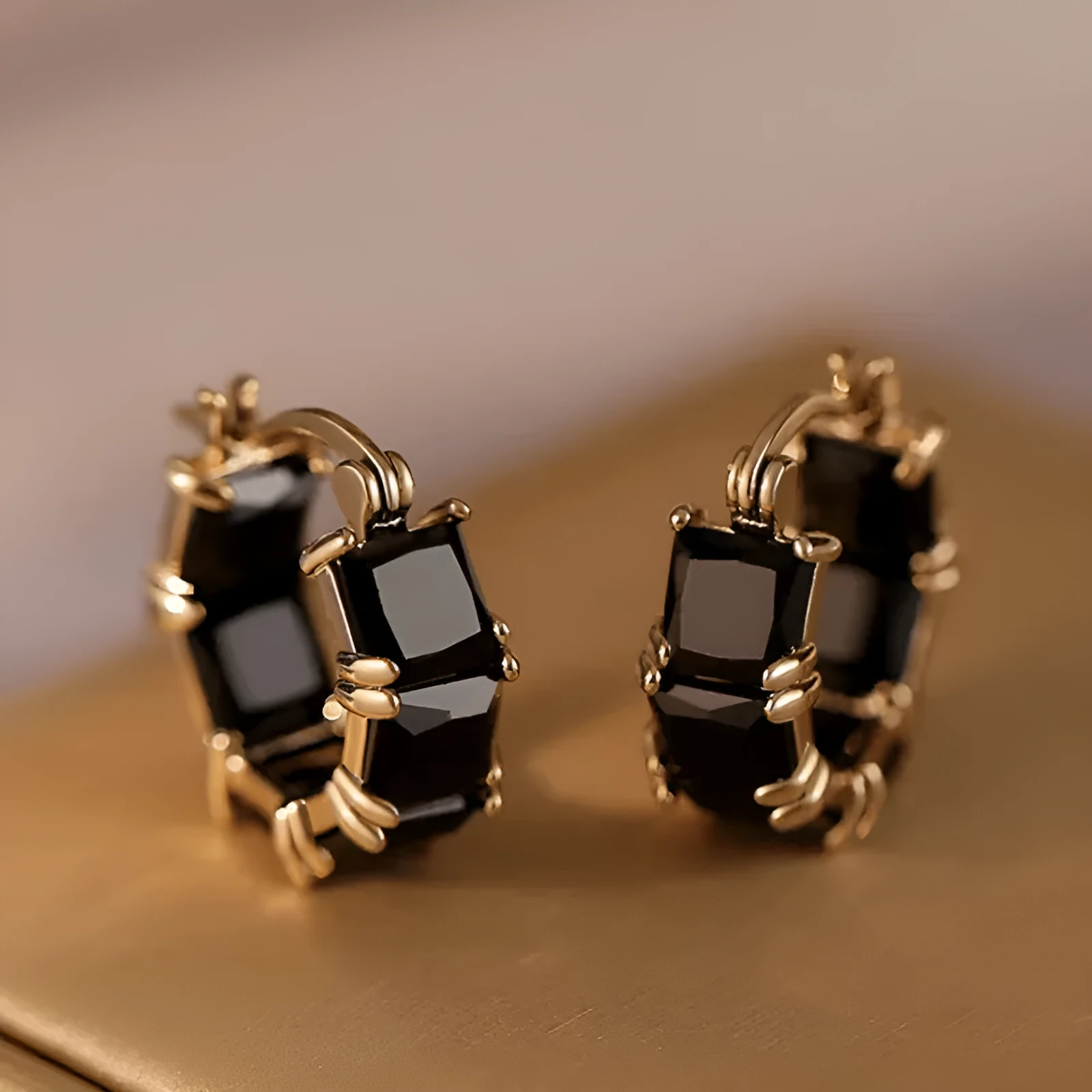 Women's geometric U-shaped gold earrings with round black zircon crystals on white background