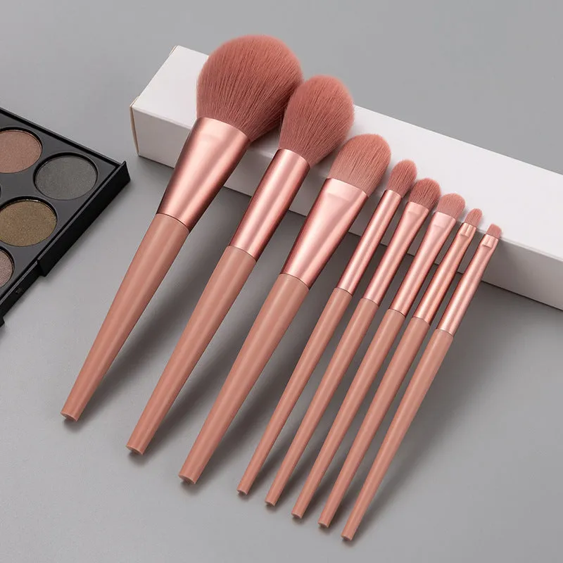Pink 8-piece makeup brush set with man-made fibre bristles and plastic handles on a light background.