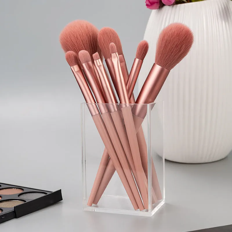 Pink 8-piece makeup brush set with man-made fibre bristles and plastic handles on a light background.