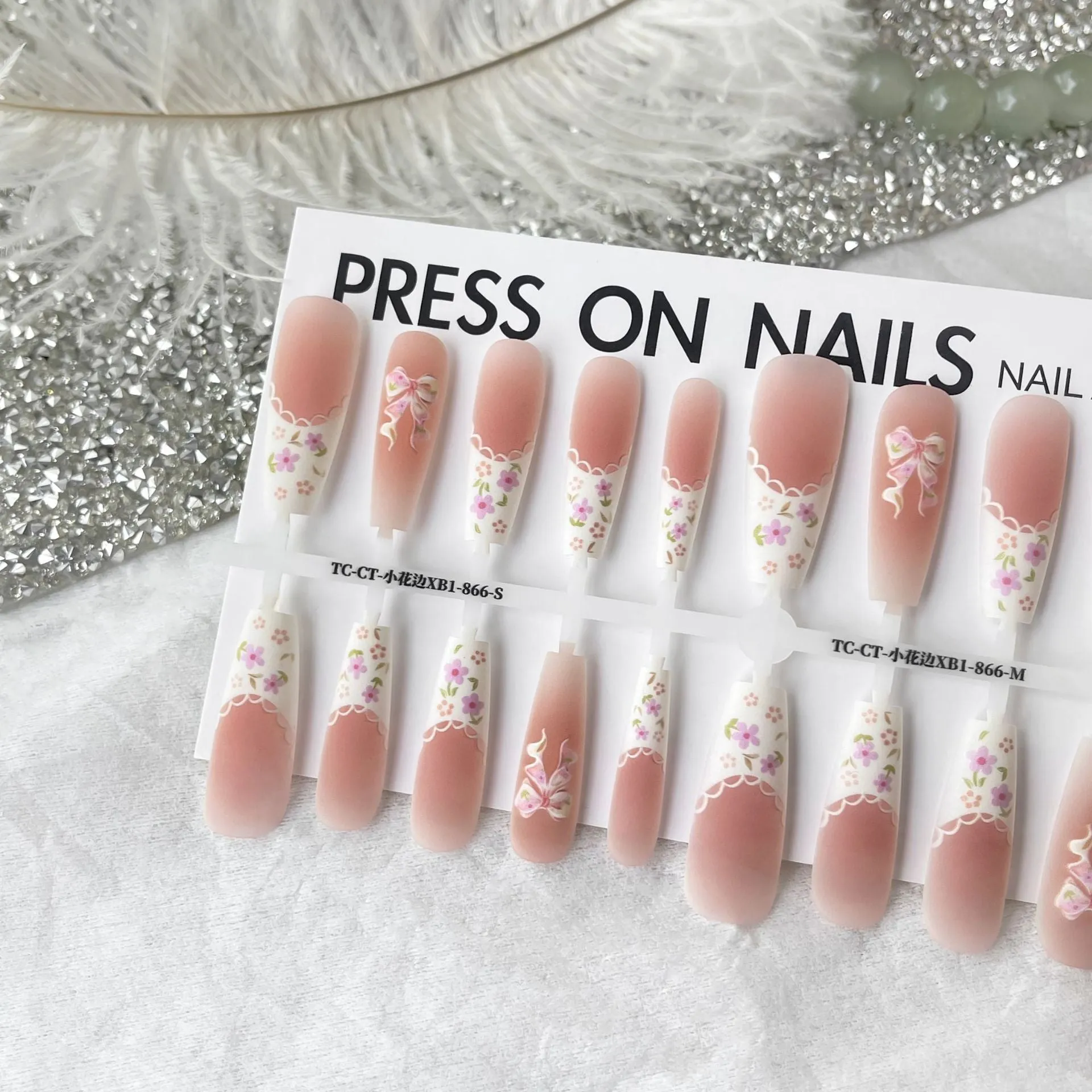 Set of 40 small floral prefabricated nail tips with long ladder velvet seal layer in white, displayed on a flat surface