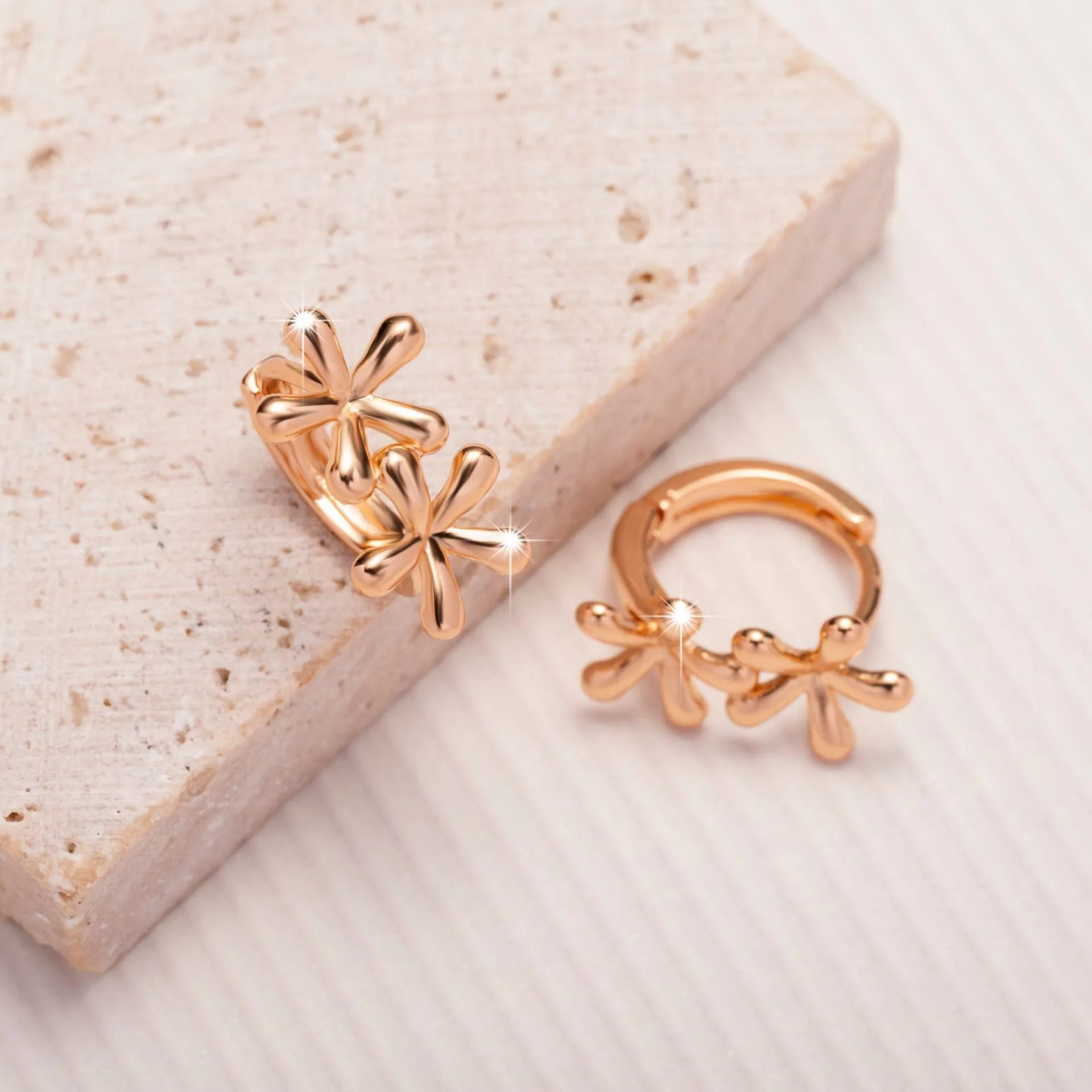 Rose gold circular earrings with a raised waterdrop floral design on a white background.