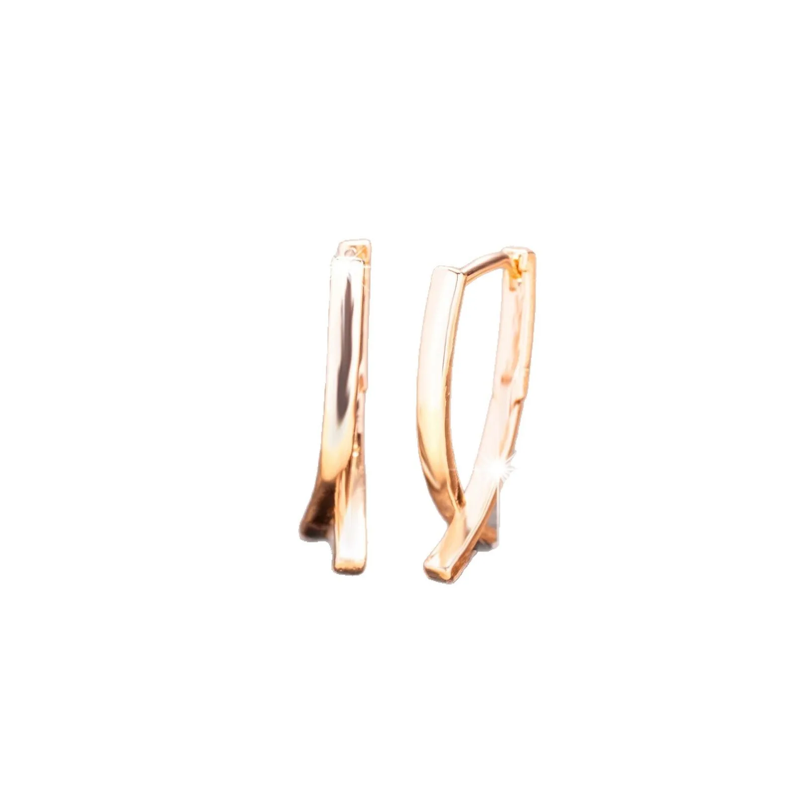 A pair of rose gold coloured cross shaped earrings made from copper on a plain background.