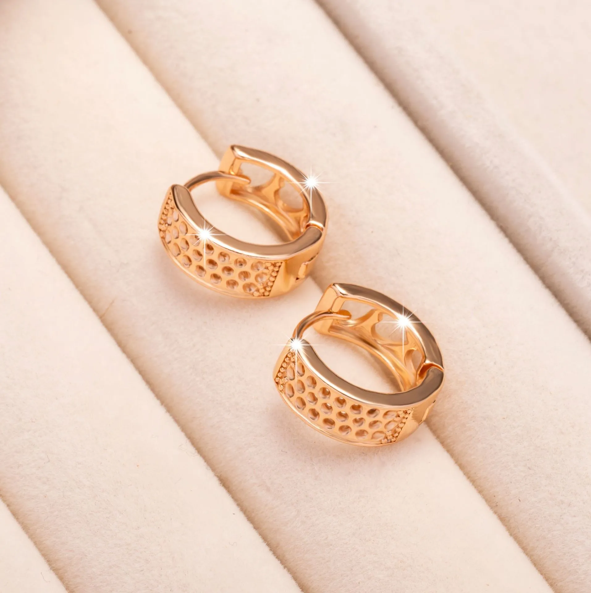 Rose gold circular earrings with three hollowed-out heart shapes.